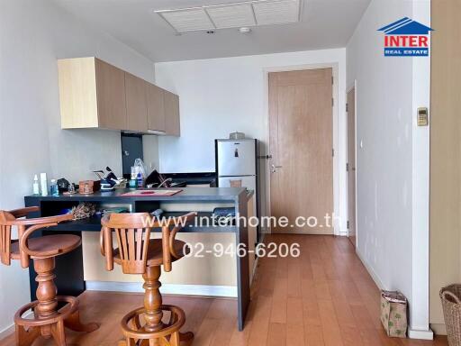 Compact kitchen with breakfast bar, wooden floor, and light wooden cabinets