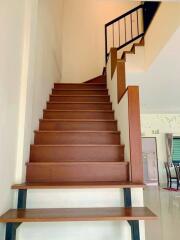 Staircase with wooden steps and metal railing leading to the upper floor