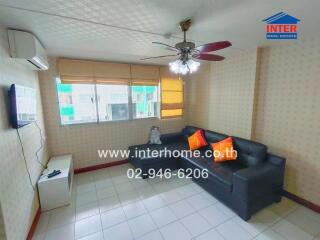 Living room with black sofa, air conditioner, ceiling fan, and wall-mounted TV.