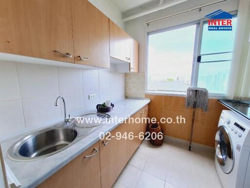 A kitchen with wooden cabinets, a sink, washing machine, and a window.