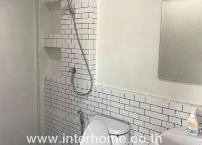 Bathroom with white subway tile, shower, toilet, and sink