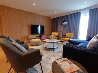 Modern living room with seating, TV, and natural light