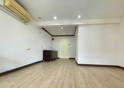 Main living area with wooden flooring, air conditioning, and a small kitchenette