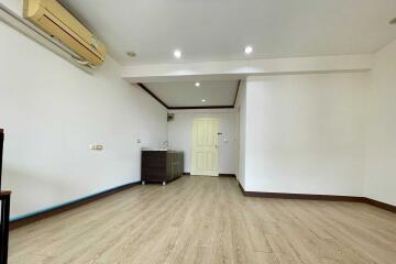 Main living area with wooden flooring, air conditioning, and a small kitchenette