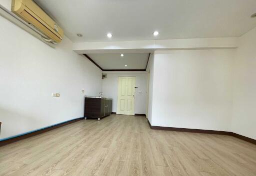Spacious living room with clean wooden flooring and a built-in air conditioning unit.