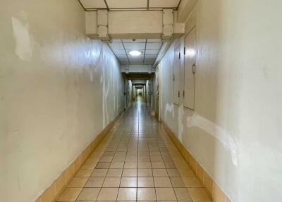 Long hallway with tiled flooring and overhead lighting