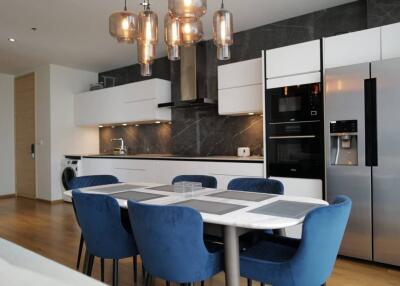 Modern kitchen and dining area with blue chairs and hanging lights