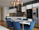 Modern kitchen and dining area with blue chairs and hanging lights