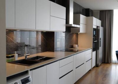 modern kitchen with white cabinets, black countertops, and built-in appliances