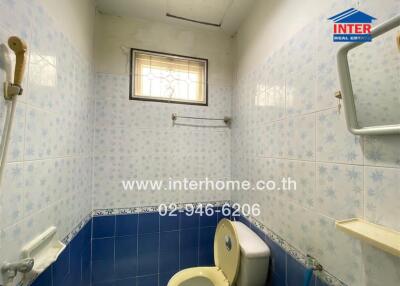 Bathroom with blue and white tiles, small window, toilet, and wall-mounted mirror