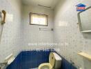 Bathroom with blue and white tiles, small window, toilet, and wall-mounted mirror