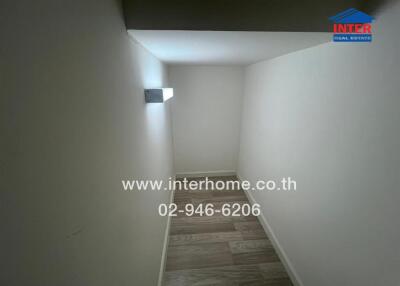 small room with wood flooring and wall light