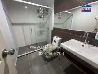 Modern bathroom with glass shower, sink, and toilet