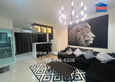 Modern living room with black sofa, patterned rug, wall art, and chandelier