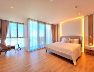 Spacious and well-lit modern bedroom with a large bed and seating area