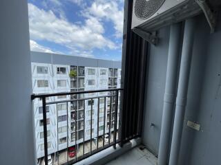 View of a balcony with a railing and an air conditioner unit, showing an apartment building across the street