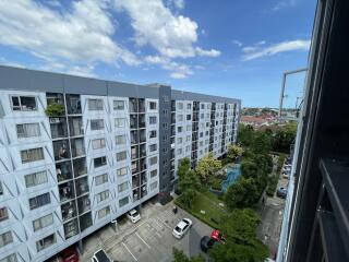 View of a multi-story residential building with parking area and garden