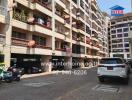 Exterior view of an apartment building with parked vehicles