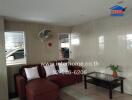 Living room with a brown sofa, a glass coffee table, and a fan on the wall