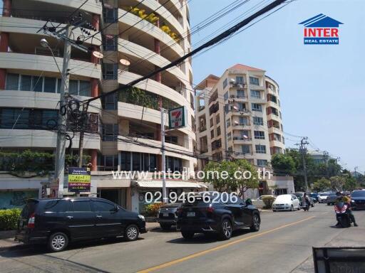 Street view of condominium buildings with vehicles parked and passing by