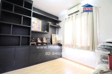 Bedroom with black shelving unit, air conditioner, window with curtains, and decorations.