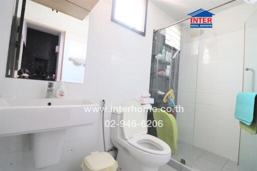 Modern bathroom with white sink, toilet, and glass-door shower.