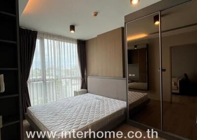 A furnished bedroom with a large window and mirrored wardrobes