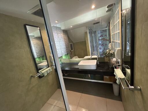 Modern bathroom with large mirror, sink, and unique wall decor