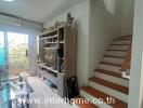 Living room with TV stand, stairway, and glass sliding door