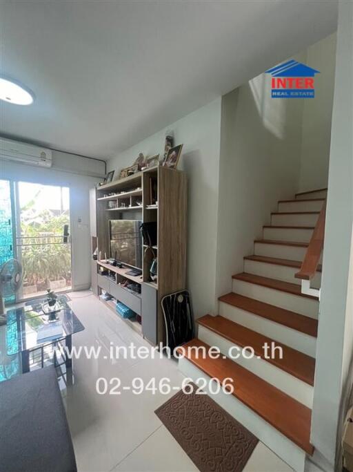 Living room with TV stand, stairway, and glass sliding door