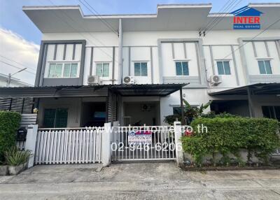 Front exterior view of a townhouse with a gated entrance and covered parking area