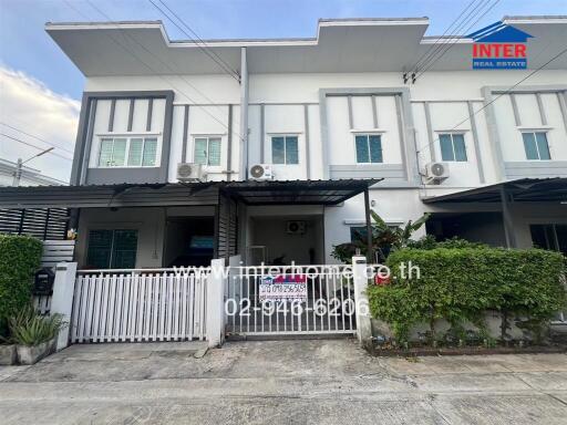 Front exterior view of a townhouse with a gated entrance and covered parking area