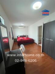 bedroom with red bedspread and wooden flooring