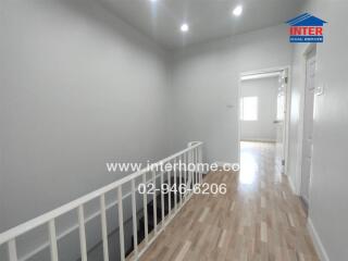 A hallway with white walls, wooden floor, and visible doors