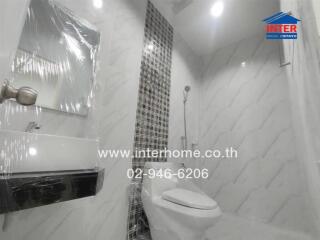 Modern bathroom with white tiles, a sink, mirror, toilet, and shower