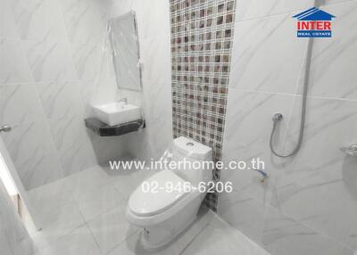 Modern bathroom with wall tiles, toilet, sink, mirror, and showerhead