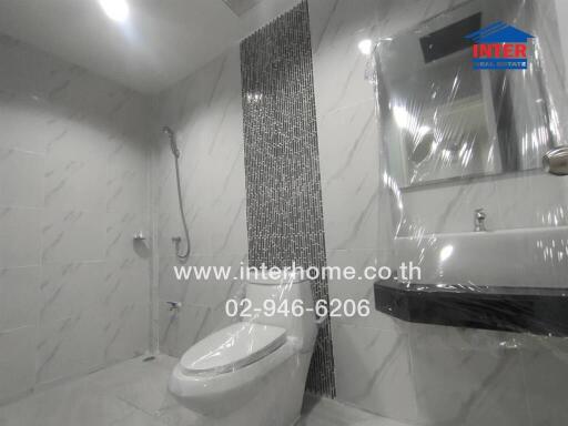 Modern bathroom with tiled walls, a shower, toilet, and sink.
