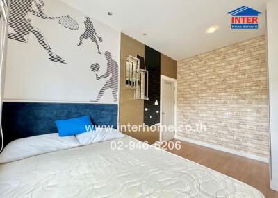 Bedroom with sports-themed wall art, a bed, and brick accent wall