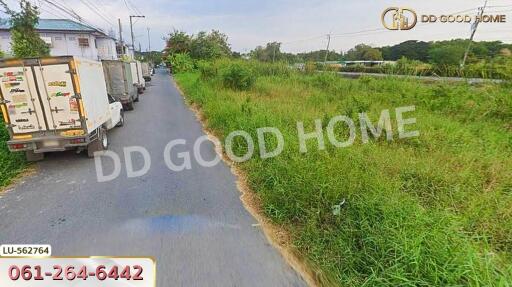 Outdoor road next to grassy field and parked trucks