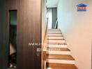 Interior view of a staircase with wooden steps and white walls