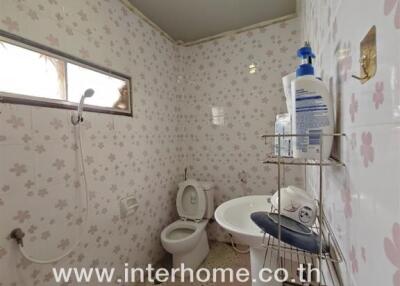 Bathroom with wall tiles, sink, toilet, and shower area