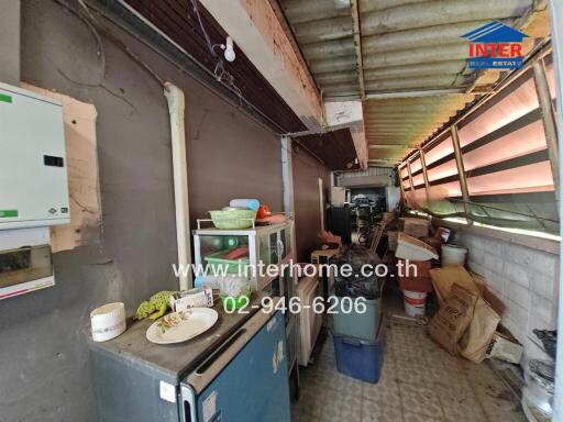 Photo of a cluttered storage area with various items stacked and a partially covered roof.