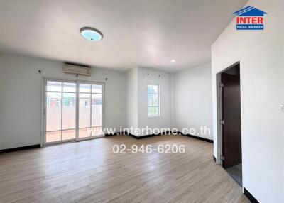 Spacious living room with large windows, wooden flooring, and air conditioning unit.