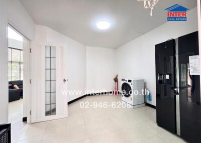 A utility room featuring a washing machine and a large refrigerator