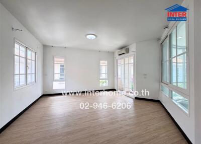 Spacious living area with wooden flooring and large windows.