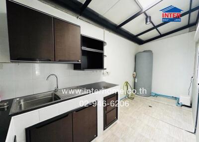 Modern kitchen area with dark cabinets and stainless steel sink