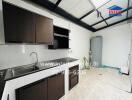 Modern kitchen area with dark cabinets and stainless steel sink