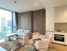 Modern living room with a view of the city skyline, featuring a seating area, dining table, and an adjacent kitchen.