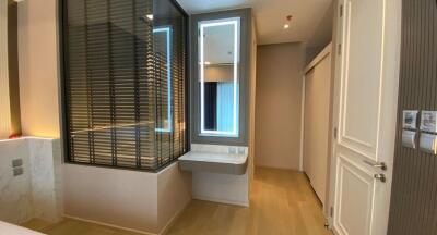 Modern bedroom with wooden flooring and a small built-in desk next to a window with blinds