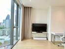 Living room with city view, large window, desk, chair, and TV